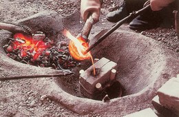 Once the metal reaches melting point, the bronze is poured into the mould, which is previously placed next to the firing pit in order to heat the stone.