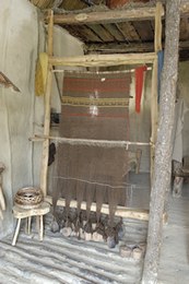 The smaller loom has been set up for weaving wool. It comprises 360 threads held by 12 weights.