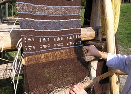 In a loom using weights, the cloth is woven from the bottom up using wooden spatulas.